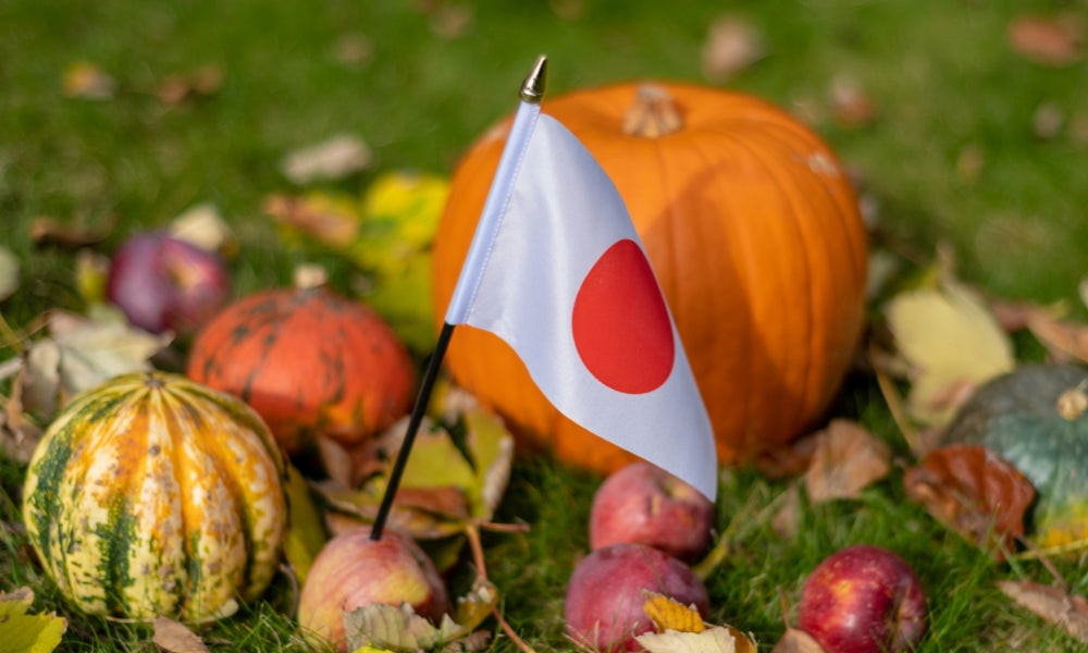 Carved pumpkin beside a Japanese flag among autumn gourds