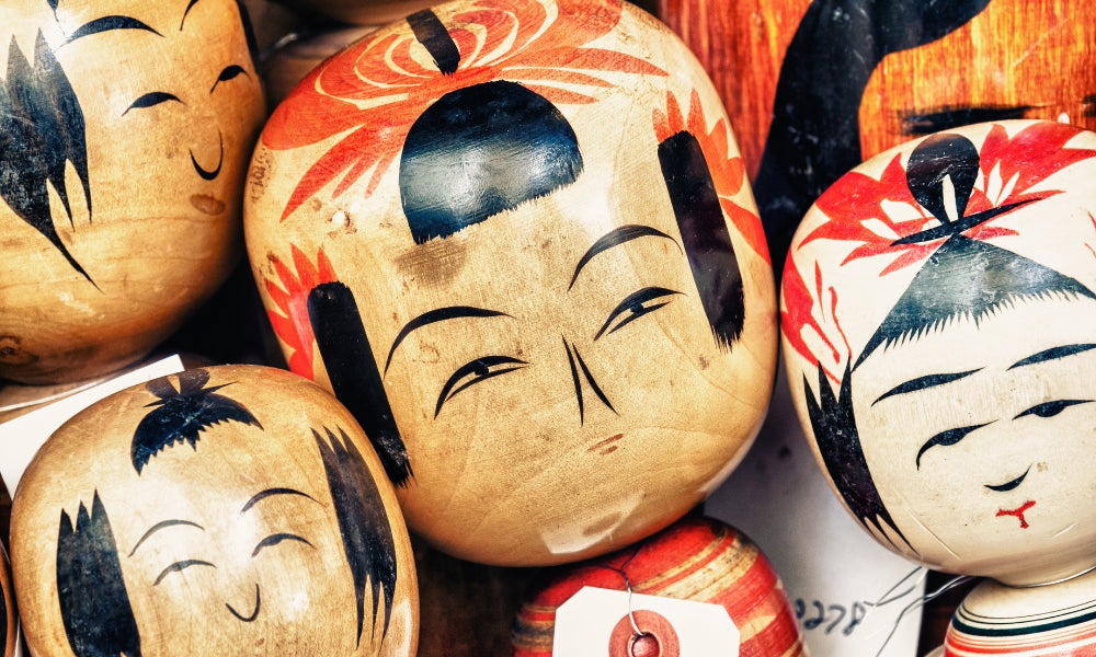 Traditional Japanese kokeshi dolls — close-up of hand-painted wooden heads from Tōhoku, with regional designs