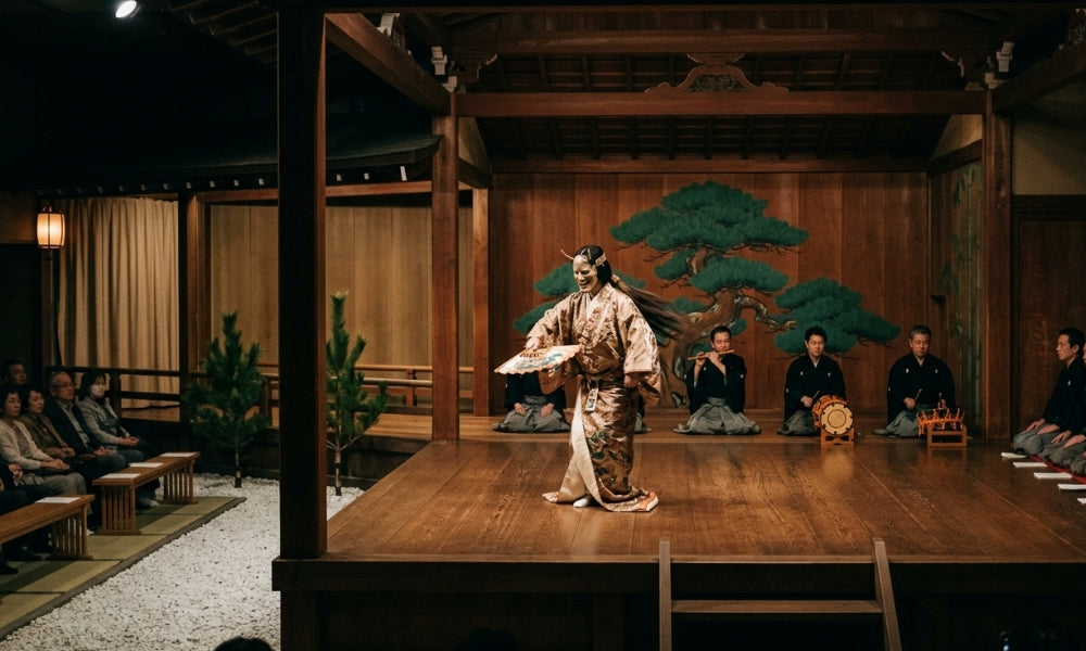 Masked Noh actor holding a fan on a cypress stage before the painted pine backboard, with seated musicians and audience