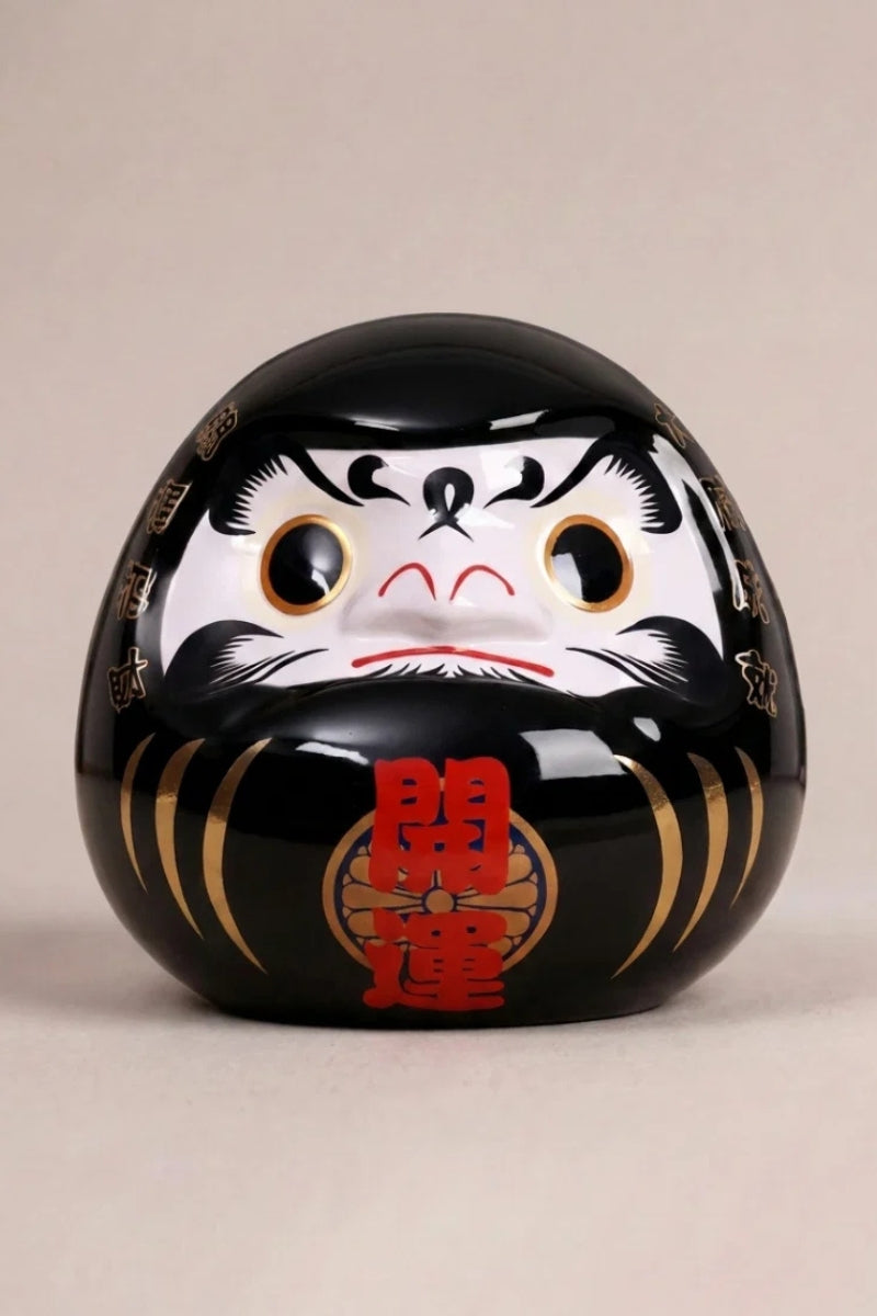 Black daruma doll marked kaiun in red with white face and bold brows, Japanese good-luck charm
