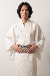 Black brocade obi belt with silver chrysanthemums, cranes and waves in blue, green and orange, worn over a kimono