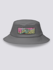 Grey bucket hat with an embroidered patch of a small vintage green and yellow train crossing cherry blossom and yellow flower fields