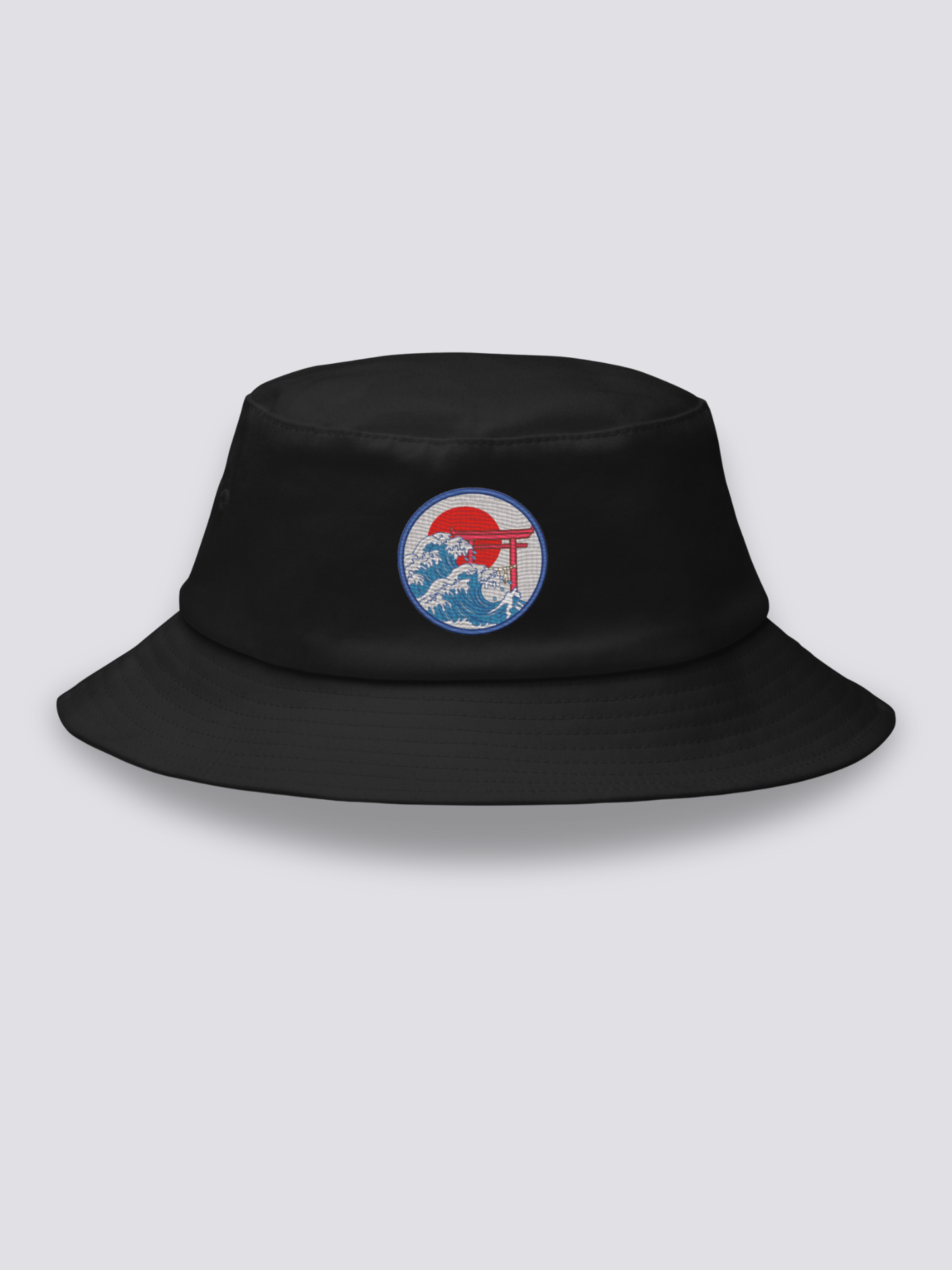 Black bucket hat with an embroidered navy medallion of a red torii half-submerged in foaming waves under a red sun