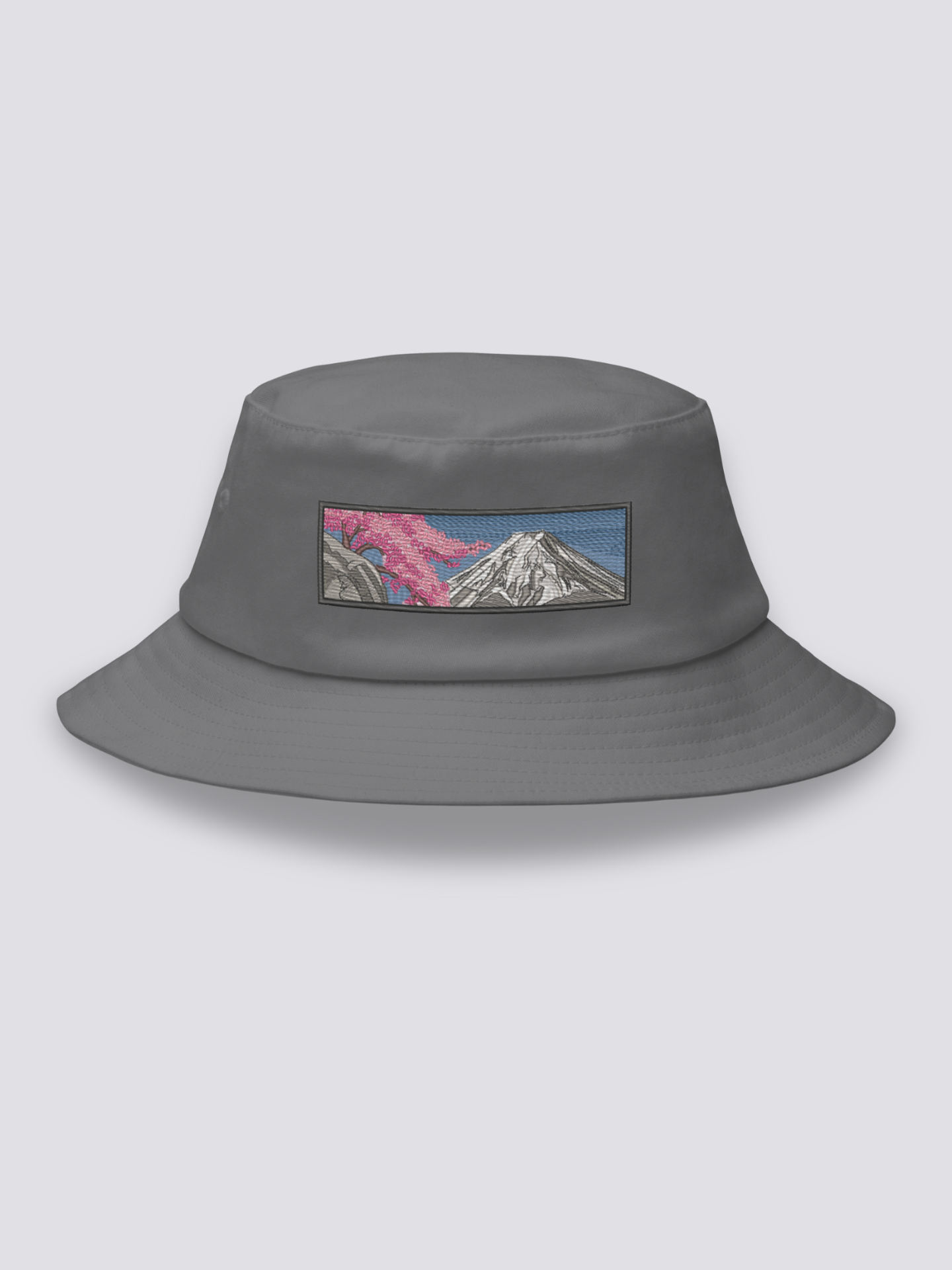 White bucket hat with an embroidered sumi-e patch of Mount Fuji in white and grey with a cherry branch over a slate sky
