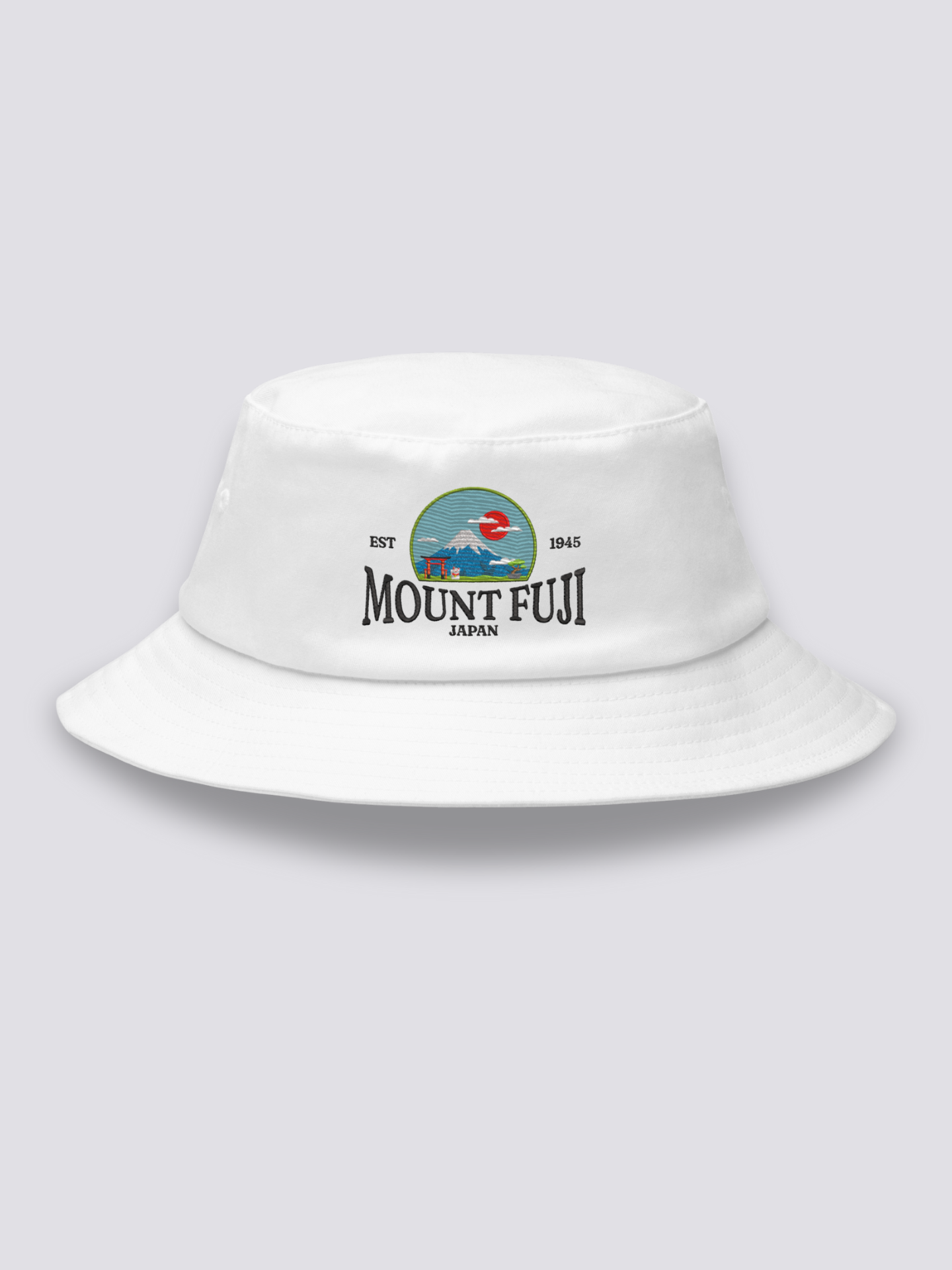 White bucket hat with an embroidered national-park style badge of Mount Fuji flanked by a torii and a red sun
