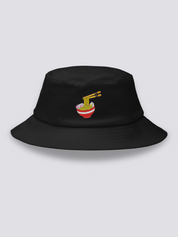 Black bucket hat with an embroidered steaming ramen bowl, noodles lifted on chopsticks and pink narutomaki