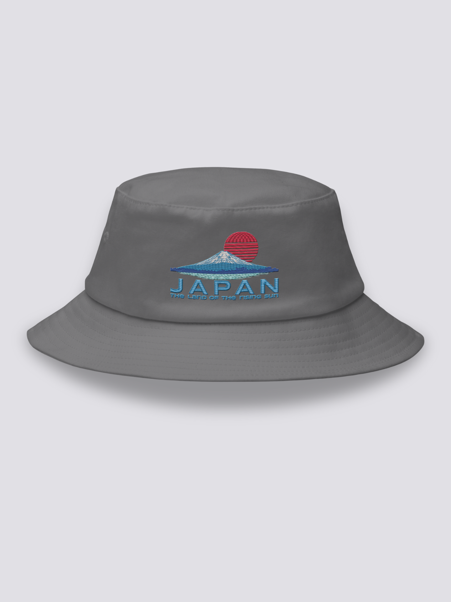 Grey bucket hat with an embroidered striped red sun above a deep blue Mount Fuji and JAPAN lettering in navy