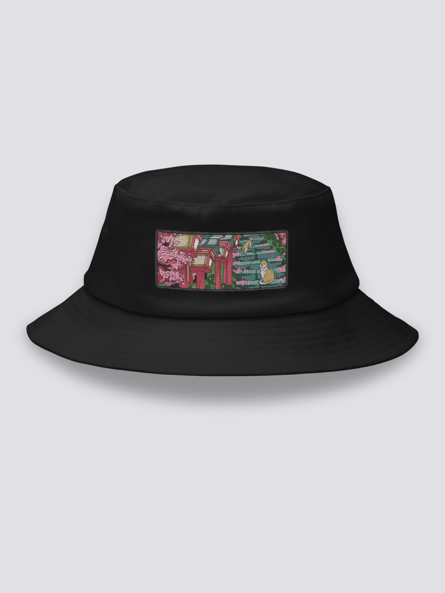 Black bucket hat with an embroidered patch of stone shrine steps under cherry blossom with two orange and white cats
