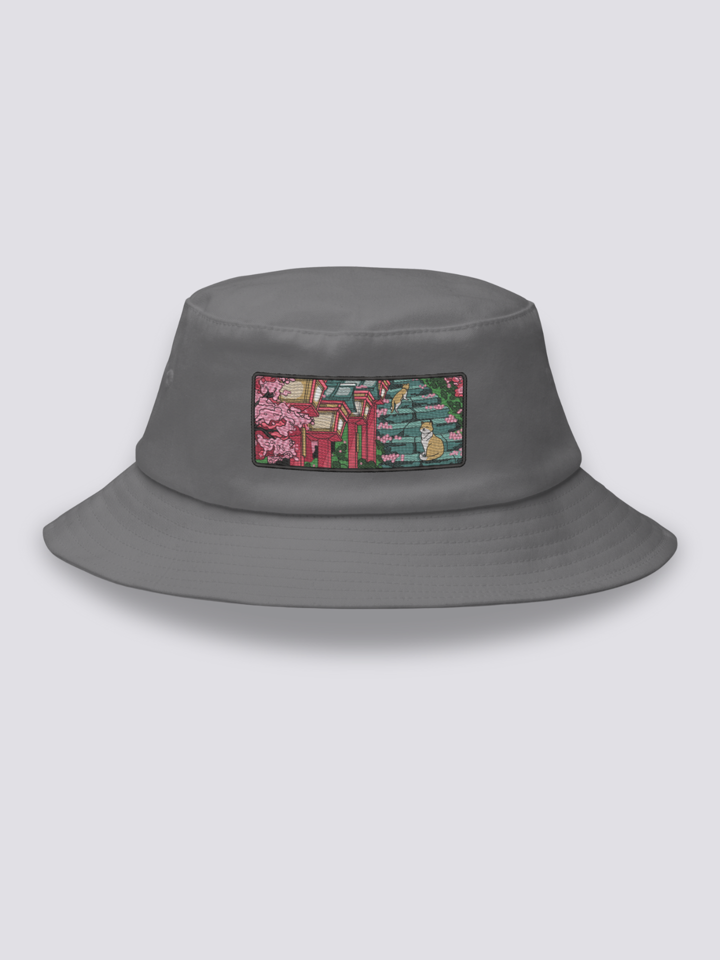 Grey bucket hat with an embroidered patch of stone shrine steps under cherry blossom with two orange and white cats