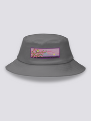 Grey bucket hat with an embroidered patch of a warbler on a cherry branch before Mount Fuji at dusk