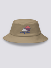 Grey bucket hat with an embroidered red striped sun behind a white cloud above JAPAN in navy lettering