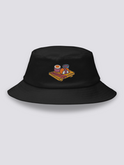 Black bucket hat with an embroidered wooden serving board holding a maki roll, a nigiri, pink chopsticks and a bowl of soy sauce