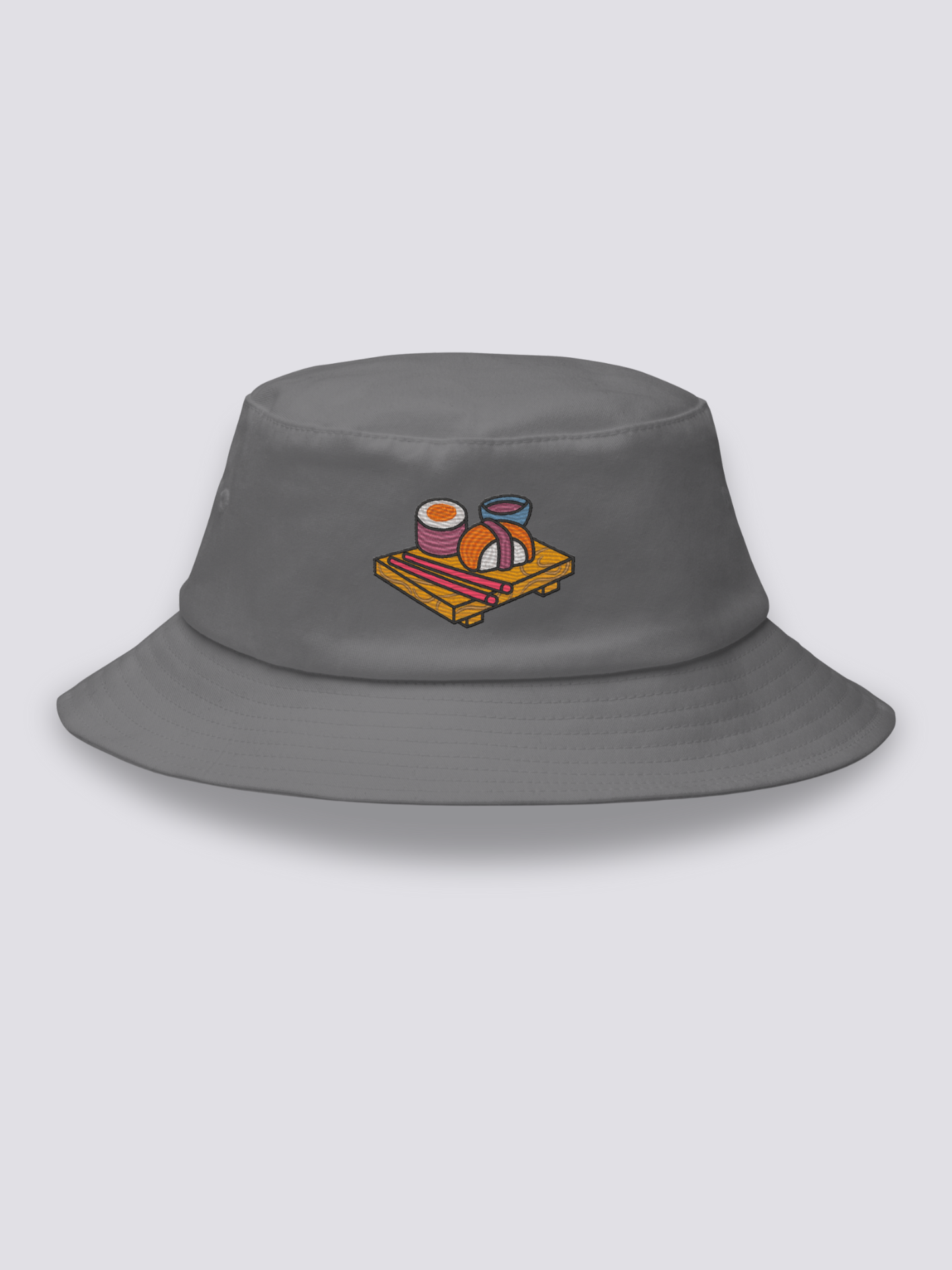 White bucket hat with an embroidered wooden serving board holding a maki roll, a nigiri, pink chopsticks and a bowl of soy sauce