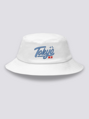 White bucket hat with Tokyo embroidered in thick blue vintage cursive script above the red kanji 東京