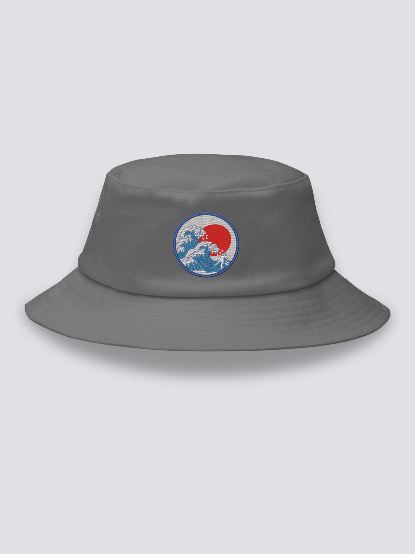 White bucket hat with an embroidered blue medallion of the Great Wave breaking beneath a full red sun