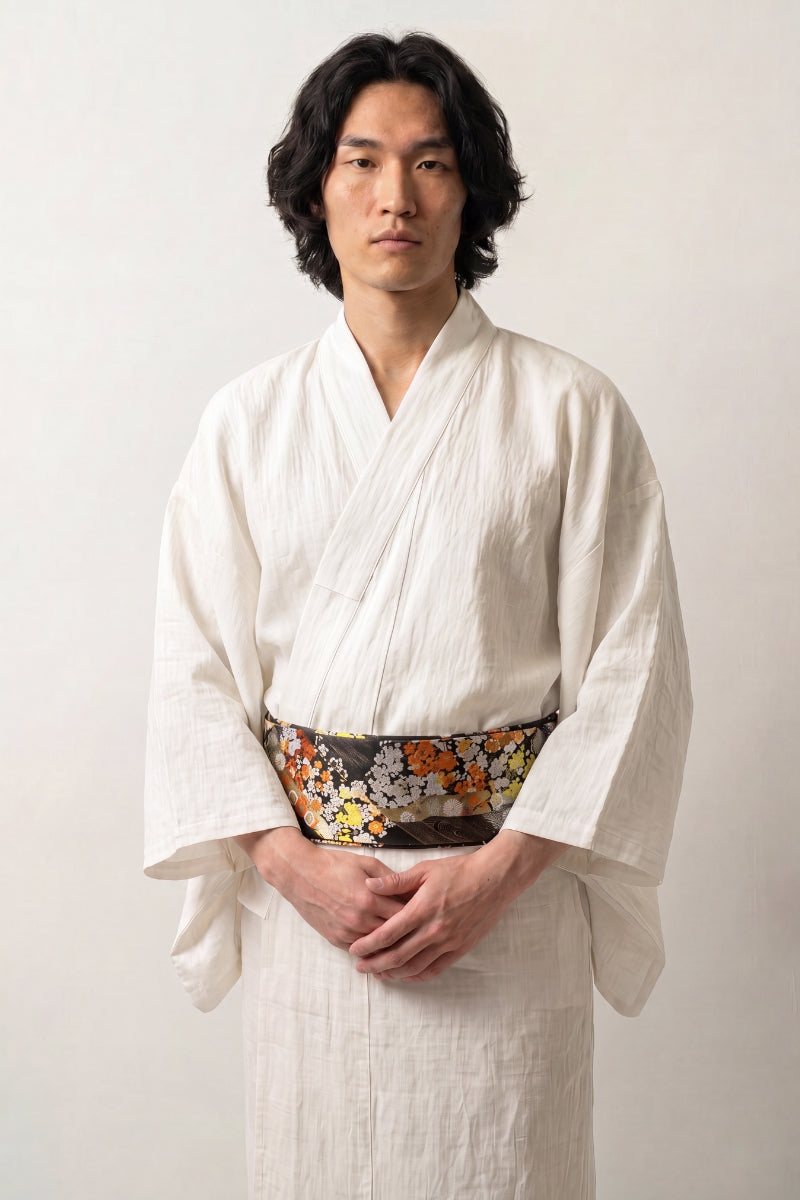 Dark brocade obi belt in an autumn palette of orange and white chrysanthemums, green foliage and golden tortoiseshell, worn over a kimono