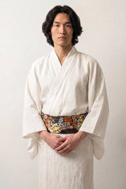 Dark brocade obi belt in an autumn palette of orange and white chrysanthemums, green foliage and golden tortoiseshell, worn over a kimono