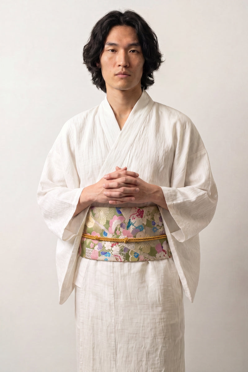 Pastel brocade obi belt with pink, green and blue flowers and gold thread, tied in a full bow over a kimono