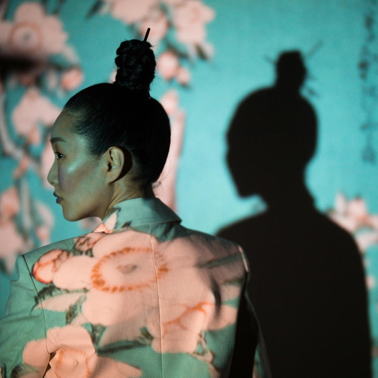 Asian model in artistic Japanese-inspired lighting wearing a modern floral jacket – Japan Clothing brand imagery.