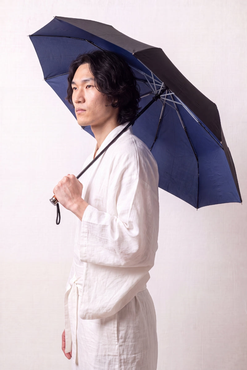 Japanese anti-UV folding umbrella in navy blue with a black UV-protective canopy and a wooden handle, shown open