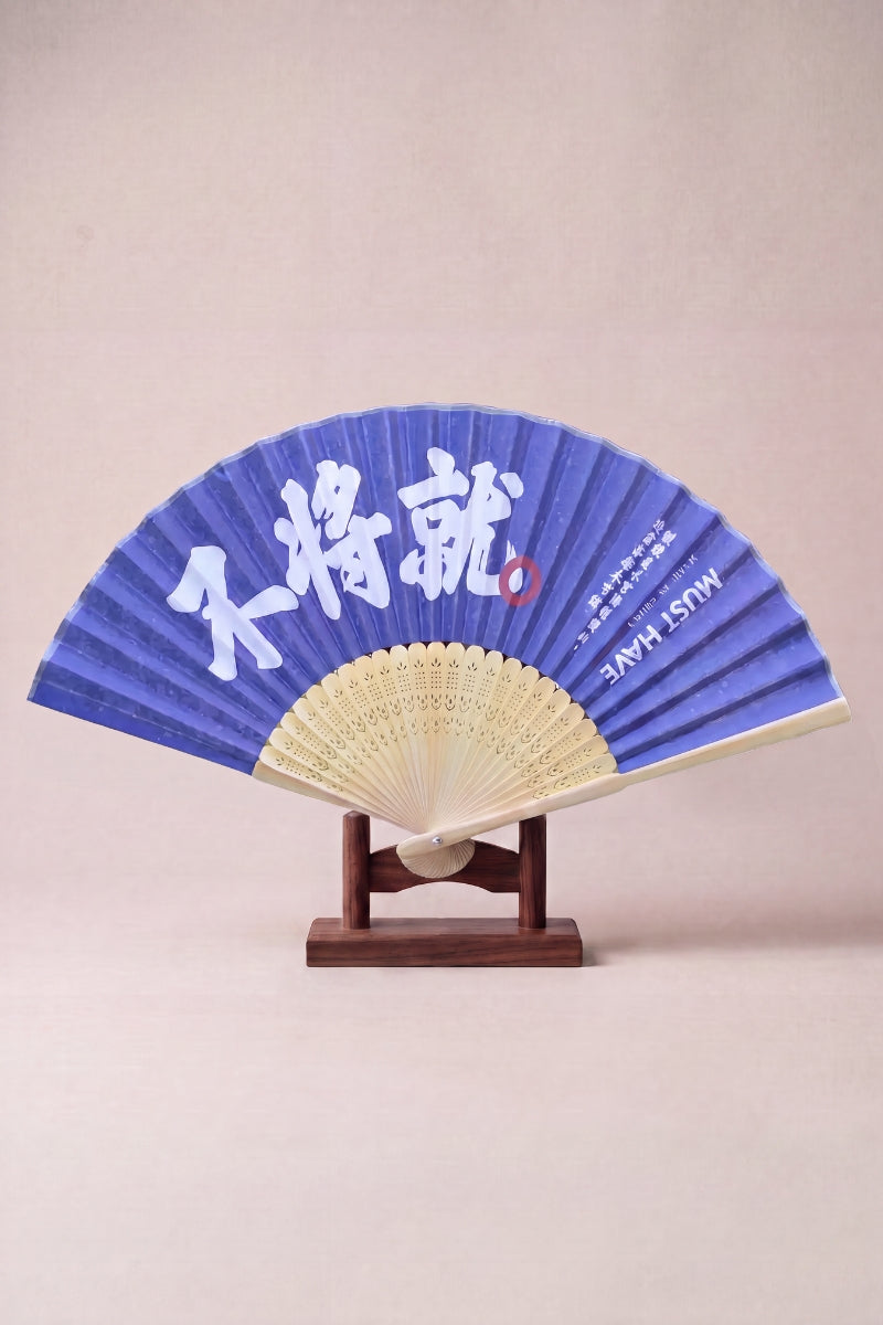 Japanese calligraphy fan with bold white brushed characters on a deep indigo leaf, mounted on carved bamboo ribs