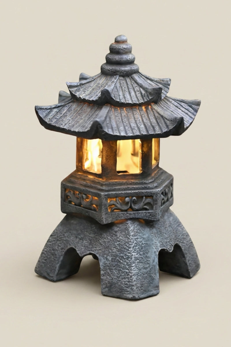 Japanese garden lantern — Japanese stone garden lantern, a grey stone garden lantern with a layered pagoda roof, glowing light inside