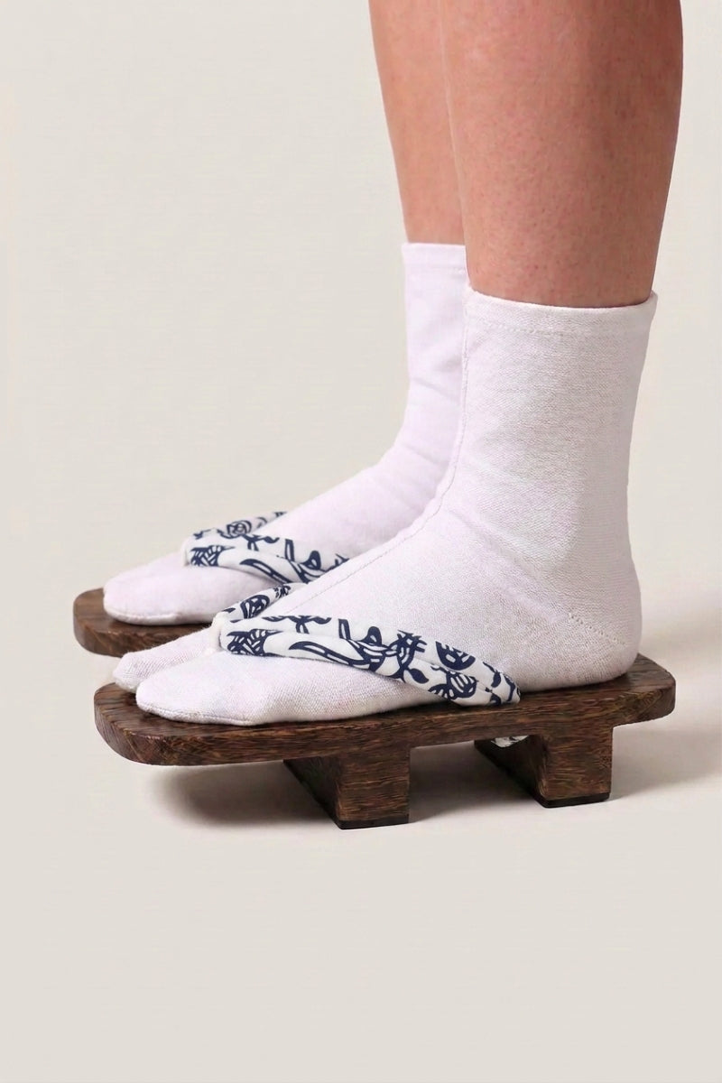 Japanese Geta 'Okayama' — wooden platform sandals with white hanao straps in a navy floral vine print, traditional two-tooth geta worn with white socks