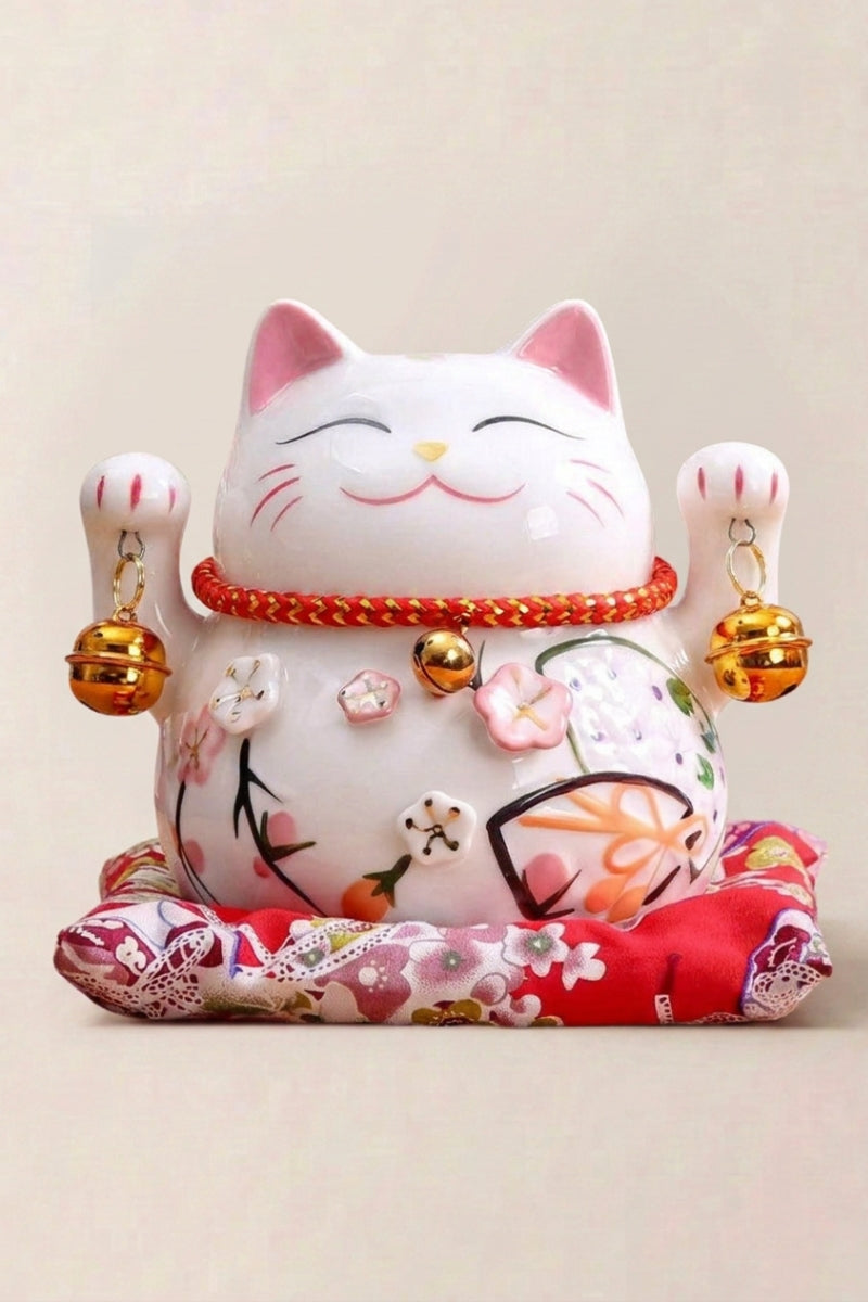Japanese Maneki Neko 'Tinkerbell' — Japanese maneki-neko lucky cat money box, white ceramic lucky cat with cherry-blossom kimono and gold bells on a floral red cushion