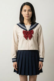 Japanese school uniform Tokyo Sailor in cream: long-sleeved sailor top with navy striped collar, wine-red bow and navy pleated skirt
