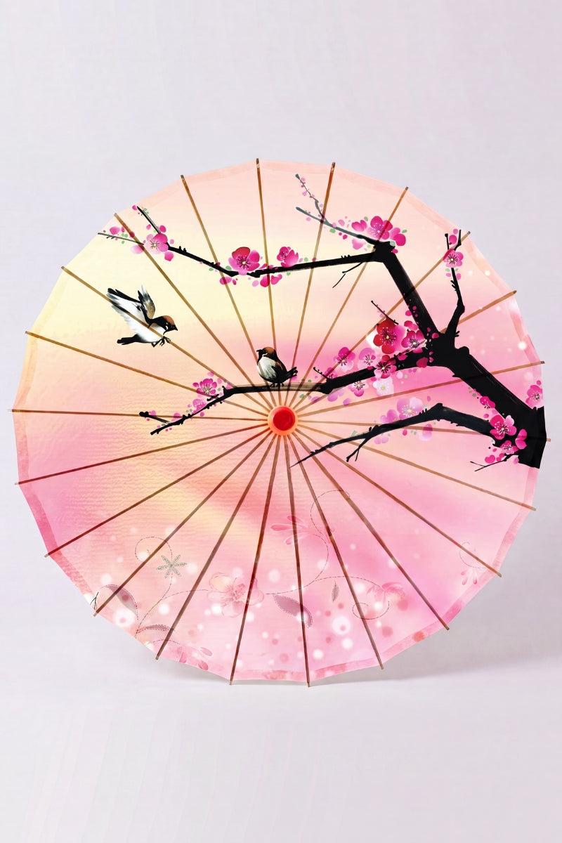 Traditional Japanese paper umbrella with fuchsia spring blossom and small sparrows on a peach-and-pink gradient, shown open on bamboo ribs