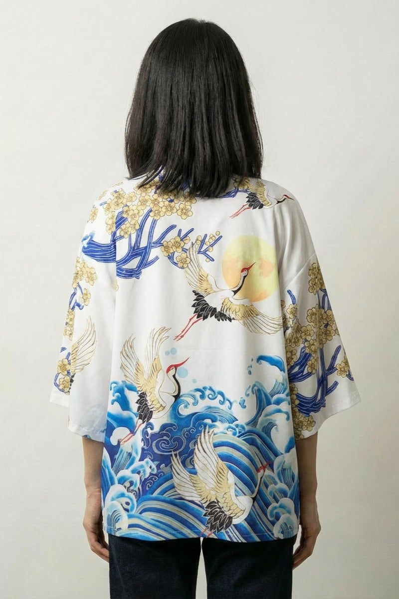 Back view of the white Sanaé kimono jacket: blue and gold waves curling beneath a crane in flight with gilded blossom drifting between