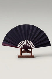 Large Japanese folding fan 'Kisho' — an oversized plain black leaf on a large bamboo folding fan, shown open on a wooden stand
