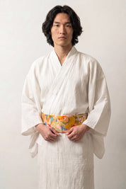 Ivory and gold brocade obi belt with large green leaves, violet and red flowers and golden fans, worn over a kimono