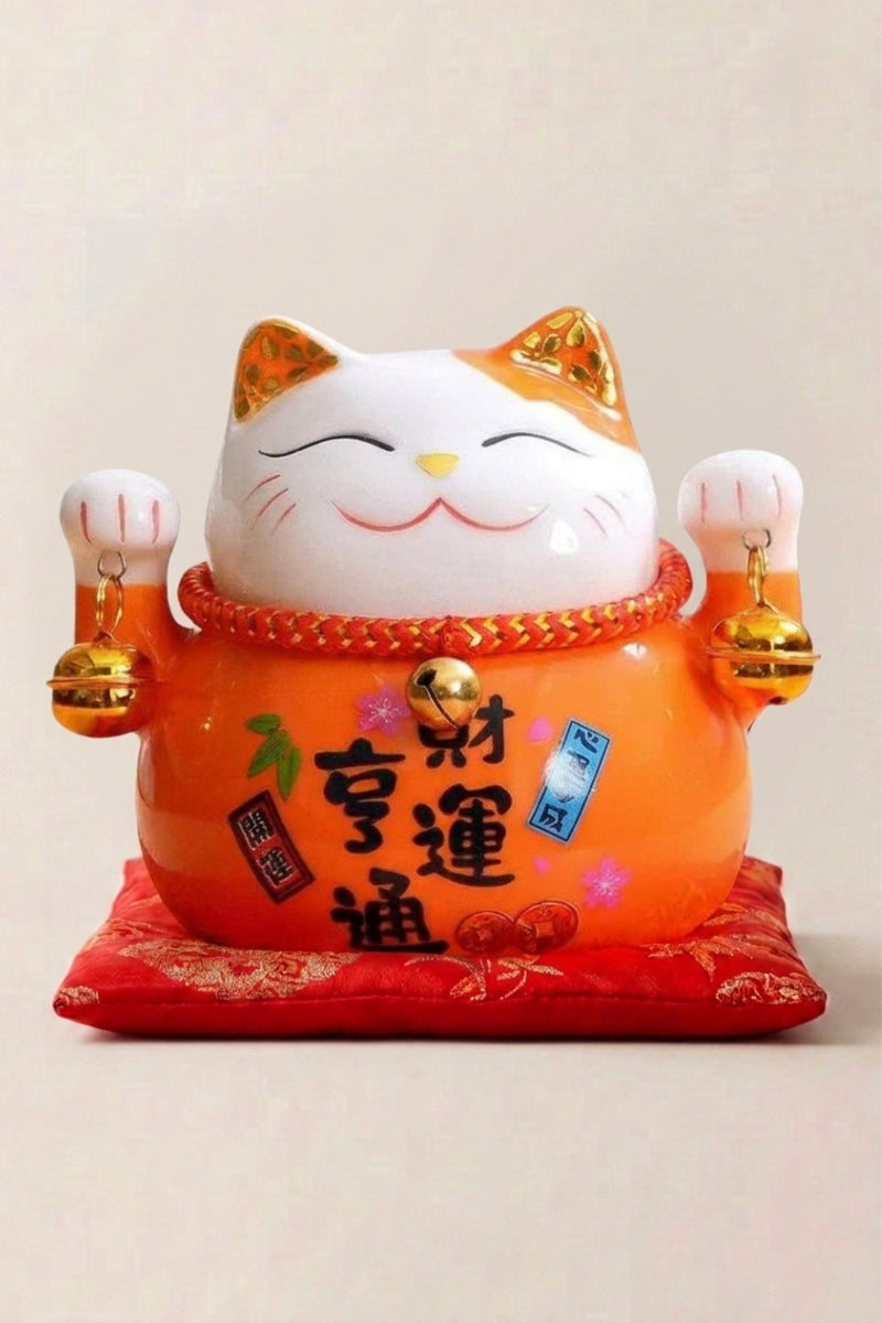 Maneki Neko 'Orange Fortune' — Japanese maneki-neko lucky cat money box, bright orange ceramic lucky cat with gold bells and red kanji for fortune on a red cushion