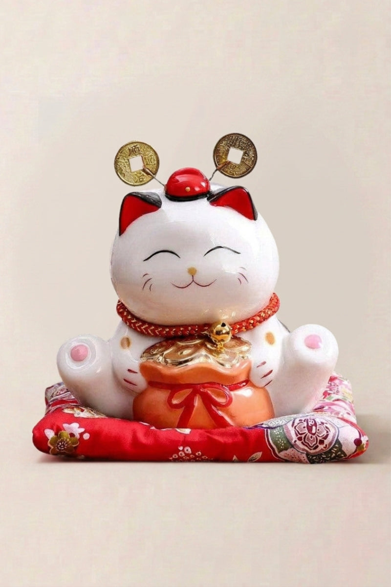 Maneki Neko Piggy Bank 'Rich Cat' — Japanese maneki-neko lucky cat money box, white ceramic lucky cat holding gold coins between two large koban on a red cushion