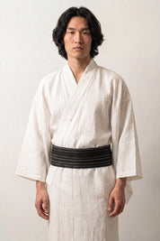 Black obi belt rippling with wavy white lines tinged with blue, worn over a white kimono