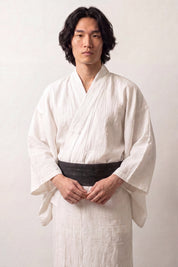 Solid black obi belt with a subtle tone-on-tone woven pattern, worn over a white kimono