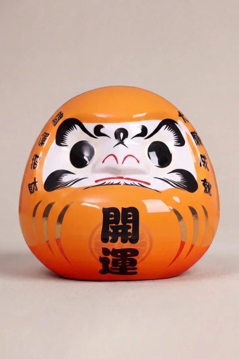 Bright orange daruma doll marked kaiun for good fortune with bold black brows, Japanese good-luck charm