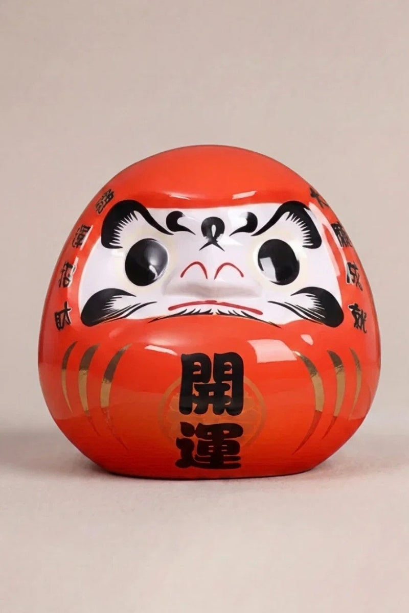 Bright red daruma doll marked kaiun with white face and fierce black brows, Japanese good-luck charm