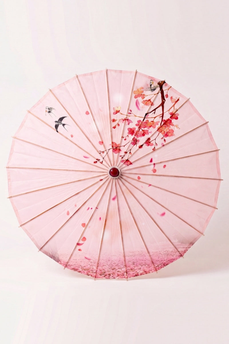 Traditional Japanese paper umbrella with cherry blossom and two darting swallows on a blush-rose canopy, shown open on bamboo ribs