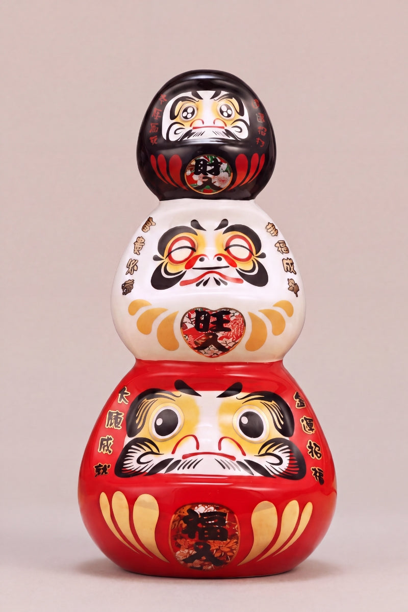 Three stacked daruma dolls in black, white and red forming a triple good-fortune tower, Japanese lucky charm