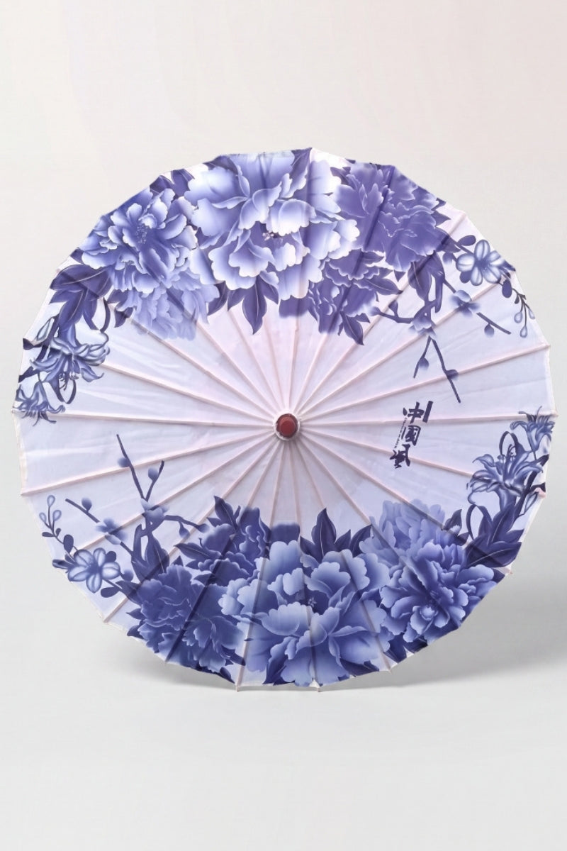 Traditional Japanese paper umbrella with cobalt and pale blue peonies in porcelain style on a white canopy, shown open on bamboo ribs