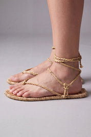 Side view of the waraji straw sandals, showing the flat woven sole and the rope lacing running from toe thong to ankle