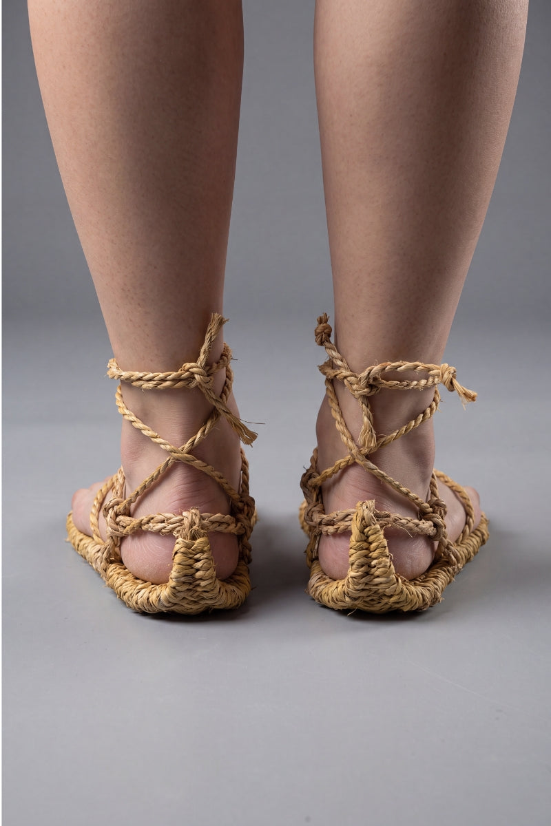 Traditional Japanese waraji sandals on bare feet, front view with the braided straw cords knotted above the ankle