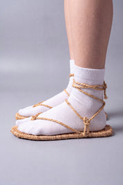 Side profile of waraji sandals worn with white tabi socks, showing the woven straw sole and ankle wrap