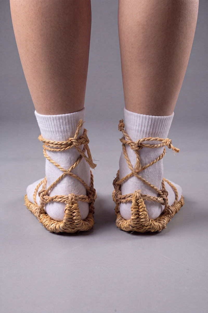 Back three-quarter view of the waraji sandals with white tabi socks, showing how the rope cords wrap and tie behind the ankle