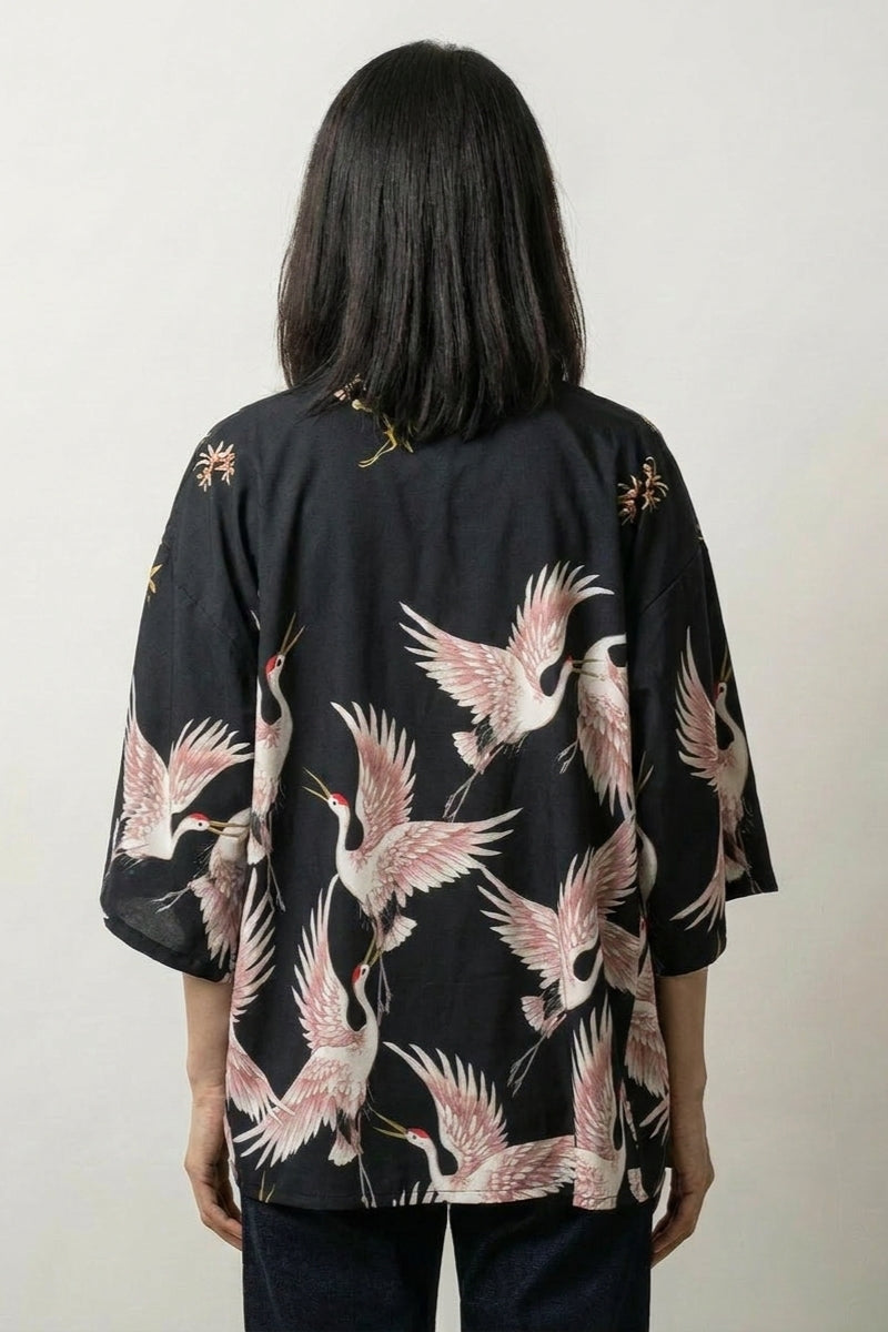 Back view of the Annaki short kimono: a scattered flock of cranes in flight, wings spread in soft pink and white against deep black