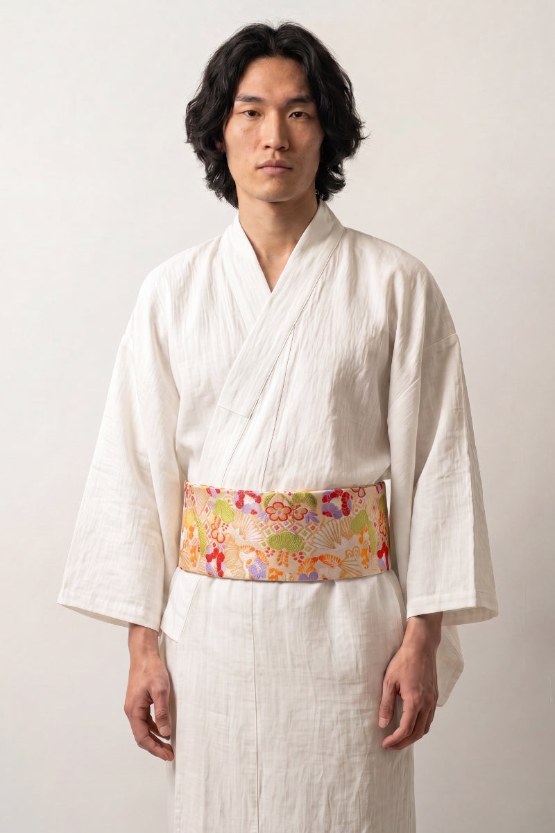 Bright golden-yellow brocade obi belt with red, blue and pink flowers among golden seigaiha waves, worn over a kimono
