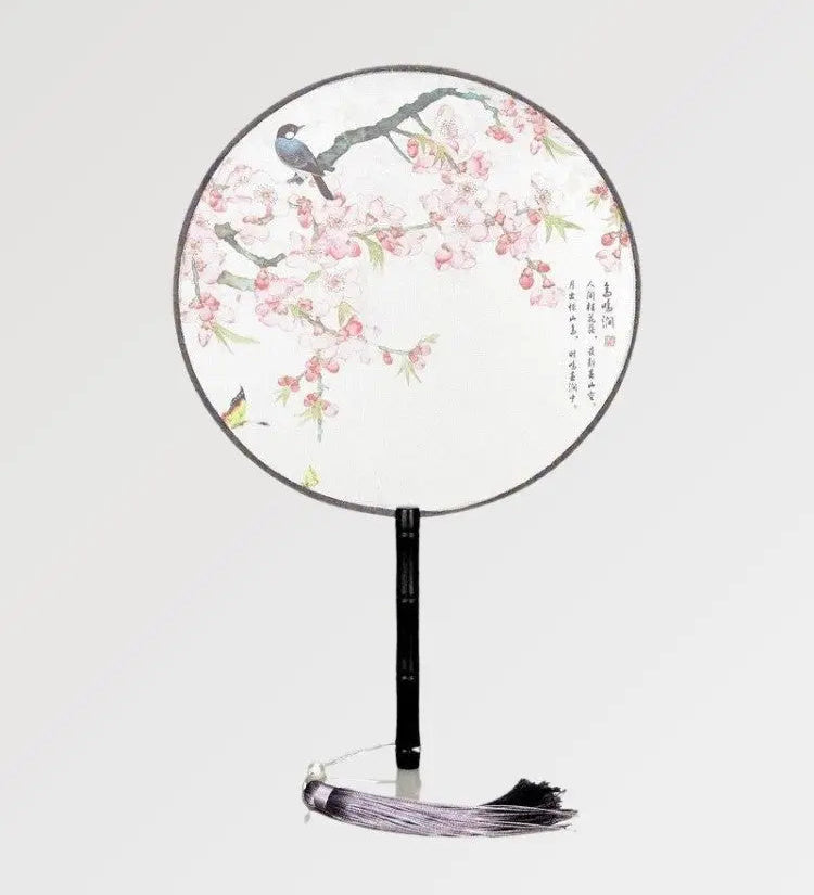 A round Japanese fan with white fabric in a pattern of flowers and birds