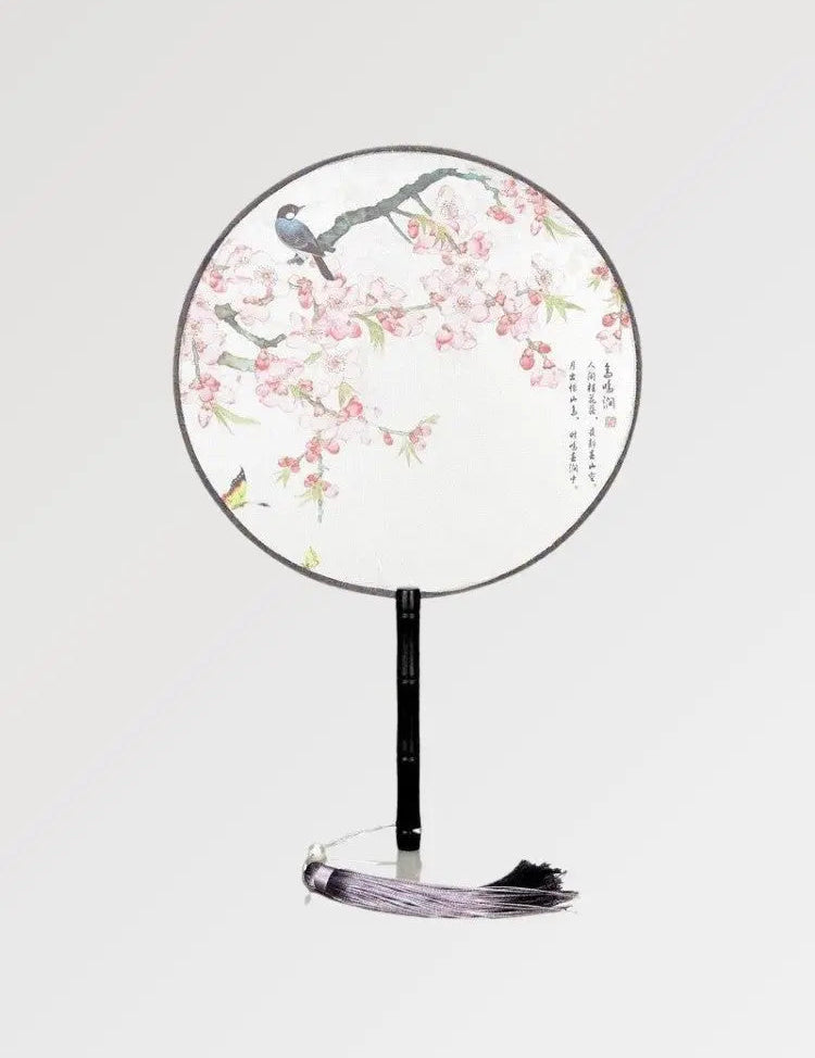A round Japanese fan with white fabric in a pattern of flowers and birds